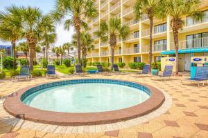 une piscine avec des chaises et des palmiers en face d'un hôtel dans l'établissement Oceanfront Condo #1125 at Summit, à Panama City Beach