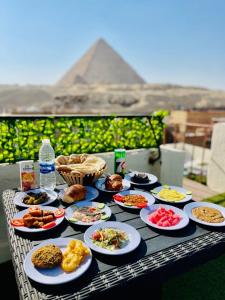 uma mesa coberta com pratos de comida com as pirâmides em Solima Pyramids View no Cairo