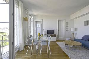 uma sala de estar com uma mesa e cadeiras e um sofá em F2 immeuble Perret avec vue à 180 ° sur la ville - Parking privatif - Hypercentre em Le Havre