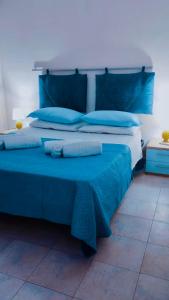 Una cama azul con almohadas azules encima. en DGS APARTHOTEL en Trapani