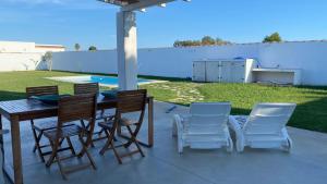 a patio with a table and chairs and a pool at Casa Costa Ecologica y de Design con Piscina, Jardin y Parking in Chiclana de la Frontera
