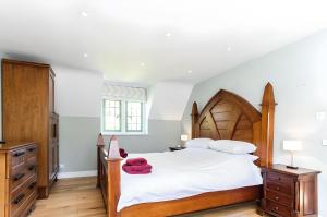 a bedroom with a large bed with a wooden headboard at Robin Cottage in Chipping Campden