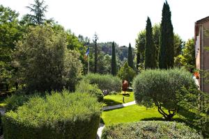 Un jardín con arbustos y árboles y una bandera. en Hostellerie Les Gorges De Pennafort, en Callas