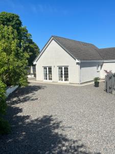 uma casa branca com uma entrada de cascalho em Lindfields em Inverness