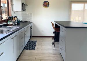 a kitchen with white cabinets and a black counter top at Casa Catrianca, Punta de Lobos in Pichilemu