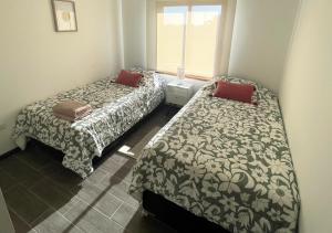 a bedroom with two beds and a window at Casa Catrianca, Punta de Lobos in Pichilemu