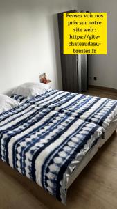 a bed with a blue and white striped blanket on it at Le château d’eau in Bresles