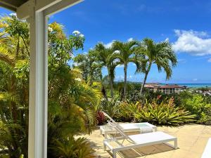 a white bench sitting on a porch with palm trees at Villa Belvedere - 5 minutes walk to the Beach in Dickenson Bay