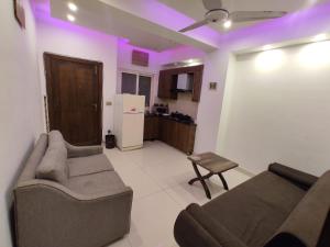 een woonkamer met een bank en een keuken met paarse verlichting bij New & elegant 1BR Flat for Families,tourists,4k Netflix,wifi,E11 Markaz in Islamabad