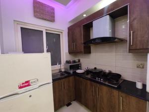een keuken met houten kasten en een witte koelkast bij New & elegant 1BR Flat for Families,tourists,4k Netflix,wifi,E11 Markaz in Islamabad