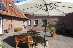 a wooden table with an umbrella and two benches at Bed and Breakfast Am Schwatten Berg in Heek