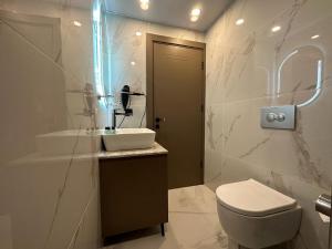 La salle de bains est pourvue de toilettes blanches et d'un lavabo. dans l'établissement Istanblu Hotel Ataşehir, à Istanbul