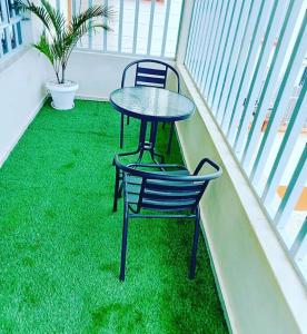 una mesa y una silla en un balcón con césped verde en Sofitel 4 bedrooms maisonette Milimani en Kisumu