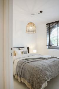 a white bedroom with a bed and a chandelier at Appartement in Antwerpen in Antwerp