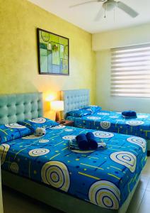 a bedroom with two beds with blue comforters at Vacaciones Playa Azul in Tonsupa