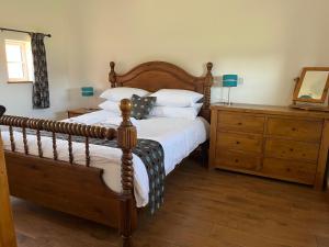a bedroom with a wooden bed and a wooden dresser at White House Farm Cottages in West Haddon