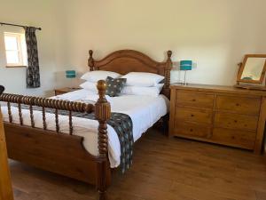 a bedroom with a wooden bed and a wooden dresser at White House Farm Cottages in West Haddon