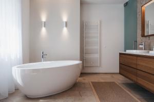 baño con bañera blanca grande y lavamanos en Das Dietrich - Landhaus 64, en Leibnitz