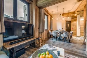 a living room with a large television and a dining room at Appartement FORNET à l'Hôtel LE VAL D'ISERE in Val-d'Isère