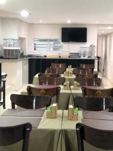 a conference room with a table and chairs and a tv at Attriun Hotel in Guarulhos