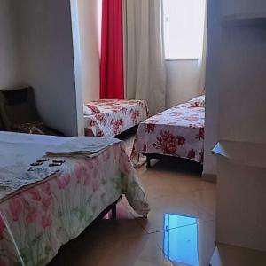 a hotel room with two beds and a window at Pousada residencial in Curvelo