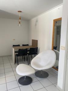 a room with two white chairs and a table at 2 quartos a beira mar da Pajuçara in Maceió