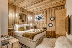 um quarto com uma cama num quarto com paredes de madeira em Appartement FORNET à l'Hôtel LE VAL D'ISERE em Val dʼIsère