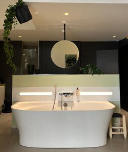 a white bath tub in a bathroom with a mirror at MiHotel Comte in Lyon