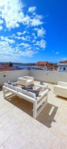 a patio with two beds and two chairs on a roof at Figueira Penthouse by the Marina in Figueira da Foz