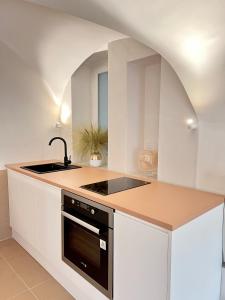 a kitchen with white cabinets and a black stove top oven at MiHotel Comte in Lyon