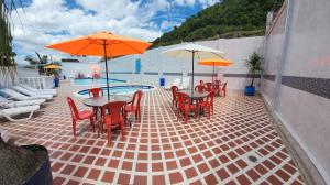 un patio con mesas y sillas con sombrillas y una piscina en Hotel Emperador, en Barbosa