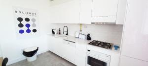 a white kitchen with a sink and a stove at Figueira Penthouse by the Marina in Figueira da Foz