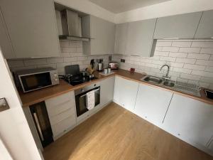 a small kitchen with white cabinets and a wooden floor at Stylish and Modern 2BR Apartment with Parking in Sheffield