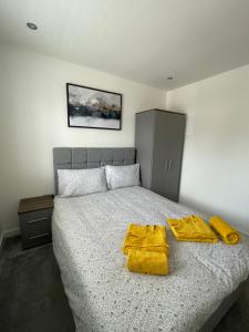 a bedroom with a bed with two yellow towels on it at Stylish and Modern 2BR Apartment with Parking in Sheffield