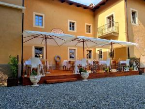 un patio con mesas y sombrillas frente a un edificio en La Carosera, en Castellengo