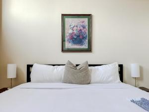 スプリングフィールドにあるSleepover 2BD 1BA Downtown Springfield Condosの白いベッド1台付きのベッドルーム1室(壁に絵画付)