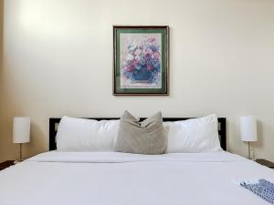 a bedroom with a white bed with a painting on the wall at Sleepover 2BD 1BA Downtown Springfield Condos in Springfield