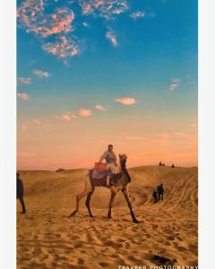 a man riding a camel in the desert at The Heritage Luxurious Camp in Jaisalmer