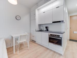 a kitchen with white cabinets and a table and a dining room at SPOT Apartments - Turun satama in Turku