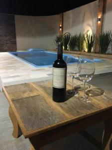 una botella de vino sentada en una mesa con dos copas en Chalé vista da serra en Delfinópolis