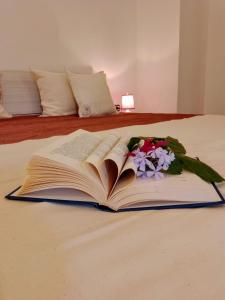 an open book on a bed with flowers on it at Appartamento Le Volte in Soleto