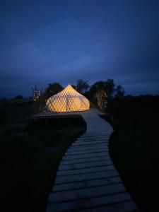 een verlichte tent op een loopbrug 's nachts bij La Colmena Glamping in El Rosario