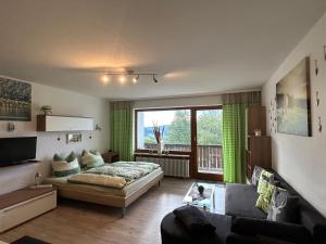 een woonkamer met een bed en een groot raam bij Fewo Ferienpark mit Swimmingpool und Aussicht 15 in Missen-Wilhams