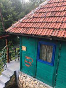 a green house with a red roof with a no door at Beli Kamen etno selo in Prokuplje