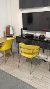 a desk with two yellow chairs in a room at דירת סטודיו גן יפיפיה קרובה לים in Tel Aviv