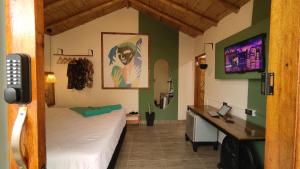 a bedroom with a bed and a desk and a tv at Puerto Bamboo in Máncora