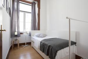 a white bedroom with a bed and a window at FLH Baixa Comfortable Apartment in Lisbon