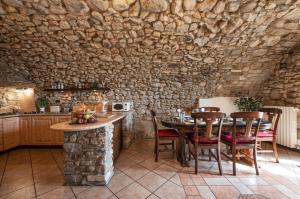 cocina con mesa, sillas y pared de piedra en Rustico Bertel, en San Zeno di Montagna