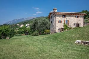 a stone house on a hill with a green field at Rustico Bertel in San Zeno di Montagna