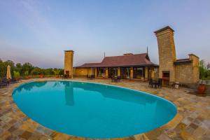 a large blue swimming pool in front of a house at Ol Pejeta Mansion in Nanyuki